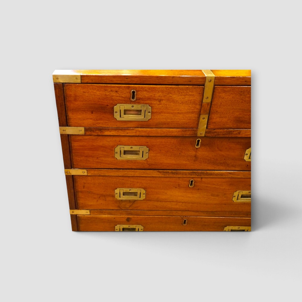 A wooden chest of drawers featuring brass corner brackets, flush handles, and two short drawers above three long drawers. View IV