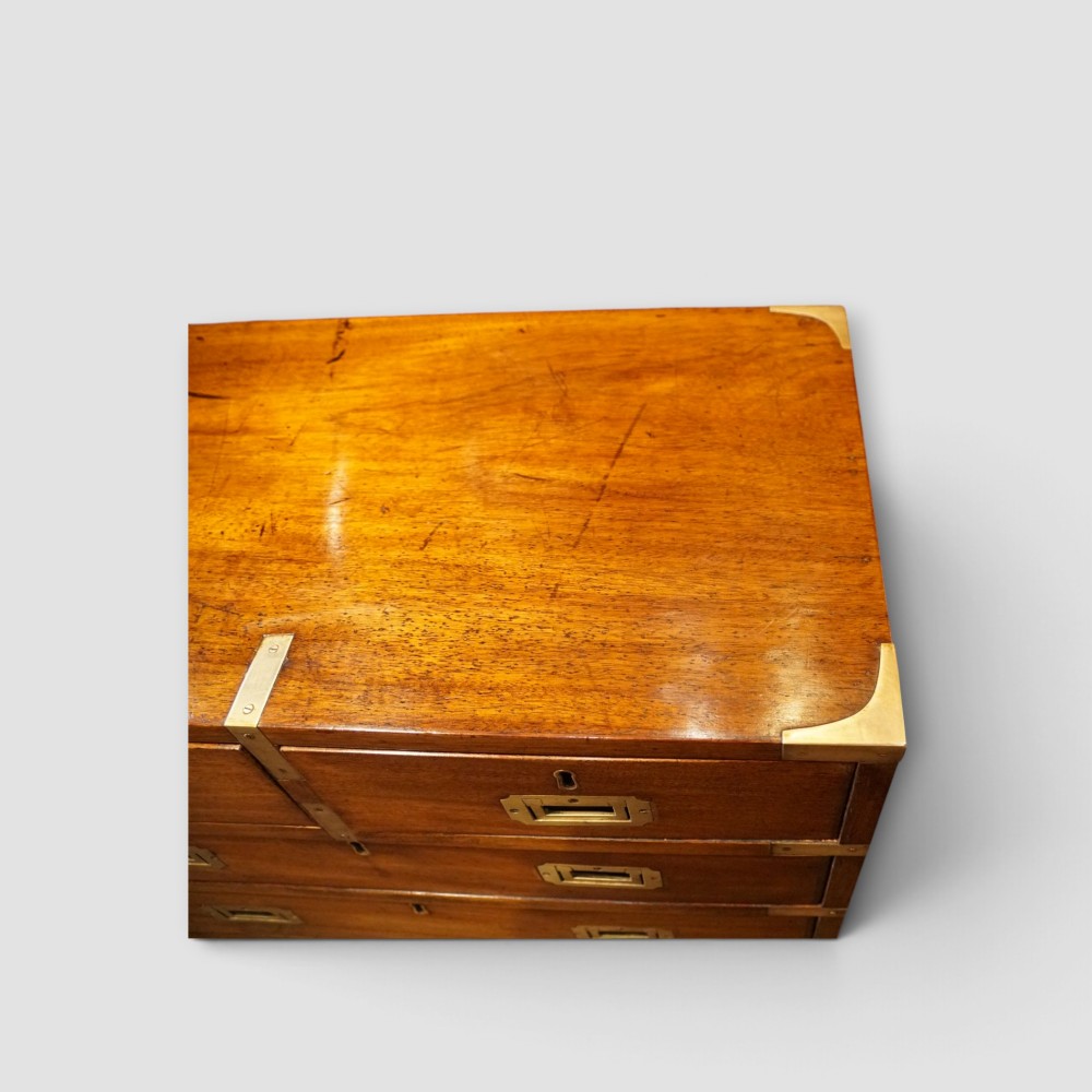 A wooden chest of drawers featuring brass corner brackets, flush handles, and two short drawers above three long drawers. View VI