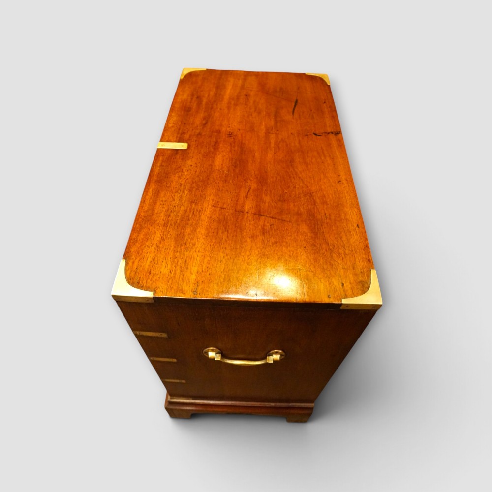 A wooden chest of drawers featuring brass corner brackets, flush handles, and two short drawers above three long drawers. View VII