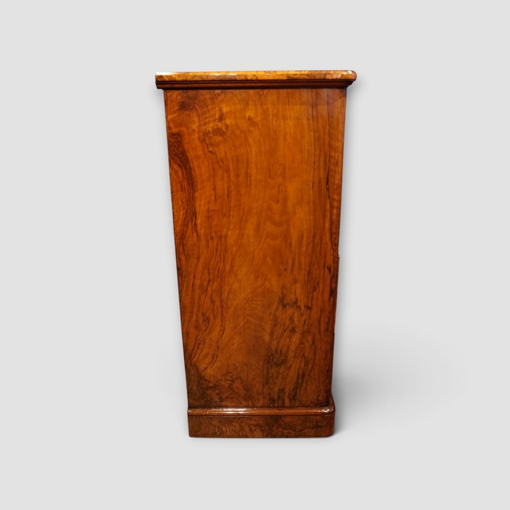 A Victorian burr walnut chest of drawers featuring two short drawers over three long drawers with turned walnut knobs and a plinth base. View VI