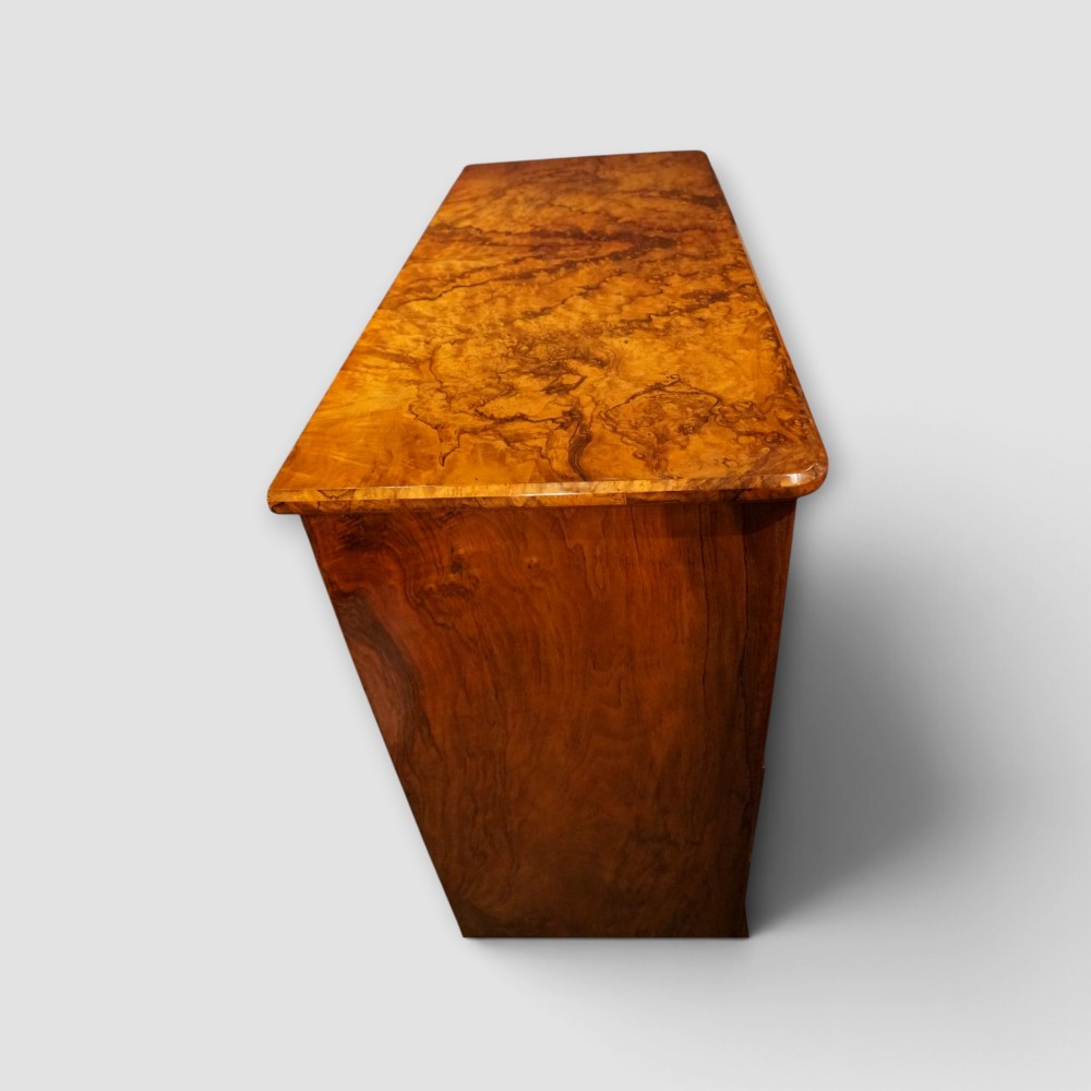 A Victorian burr walnut chest of drawers featuring two short drawers over three long drawers with turned walnut knobs and a plinth base. View IX