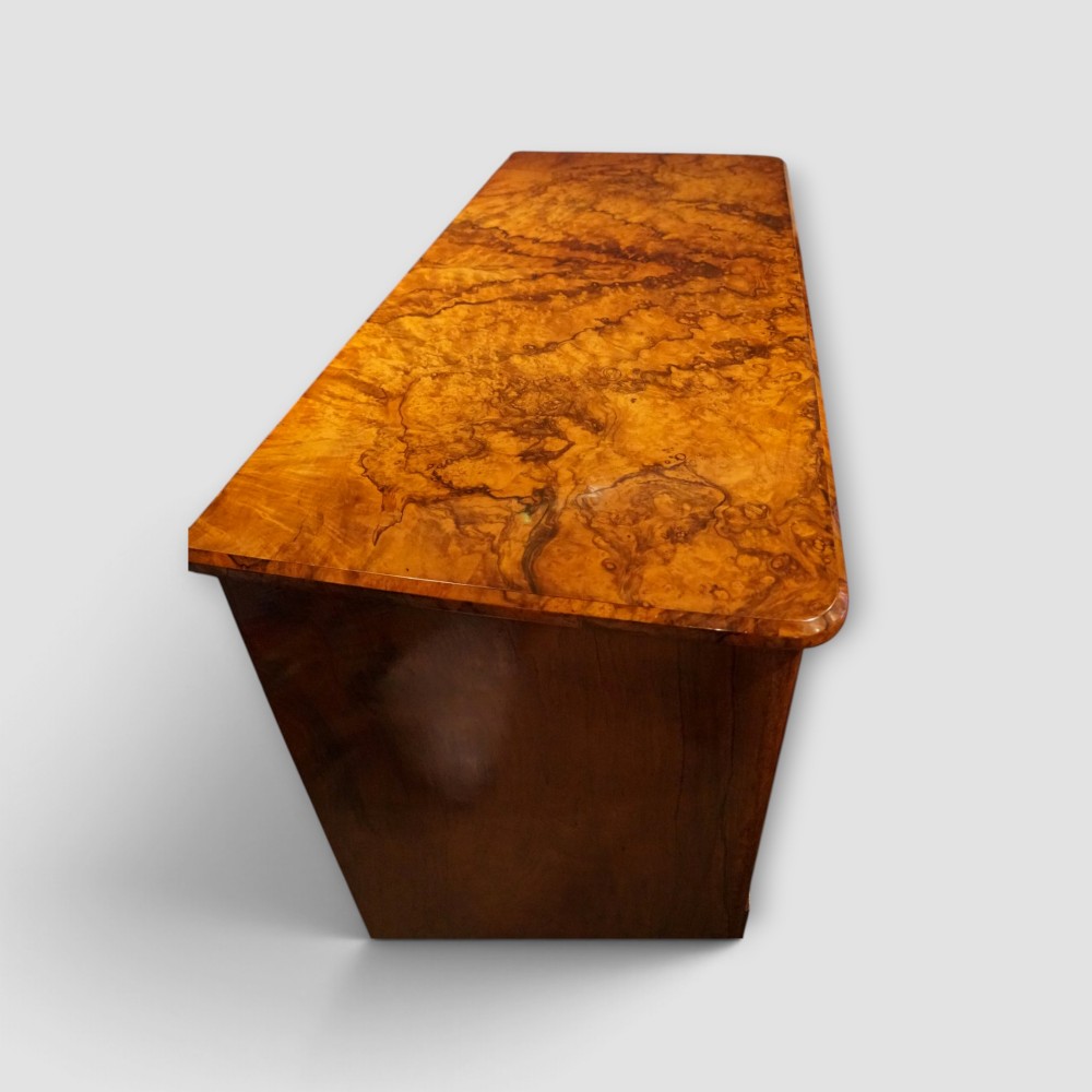 A Victorian burr walnut chest of drawers featuring two short drawers over three long drawers with turned walnut knobs and a plinth base. View X