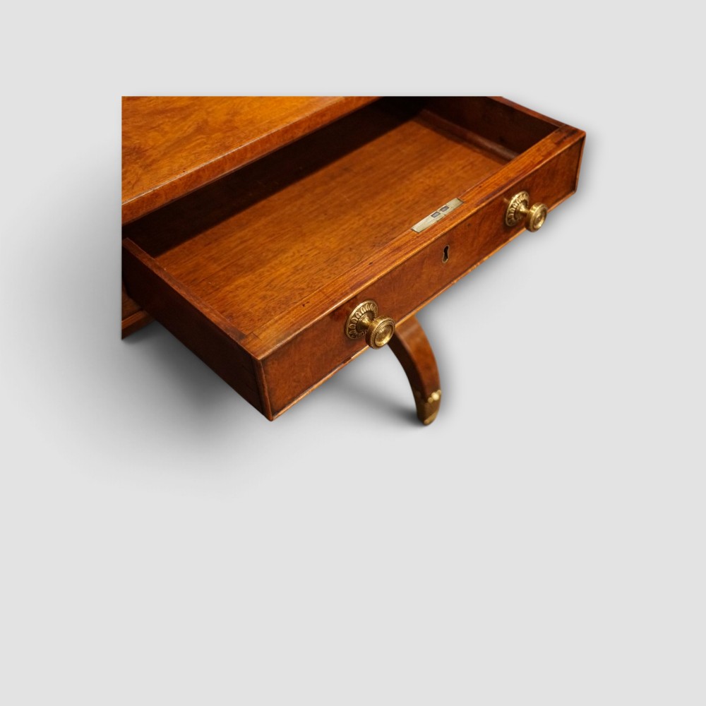 A Regency burr satinwood sofa table with drop leaves, two frieze drawers, brass handles, and splayed legs on castors. View V