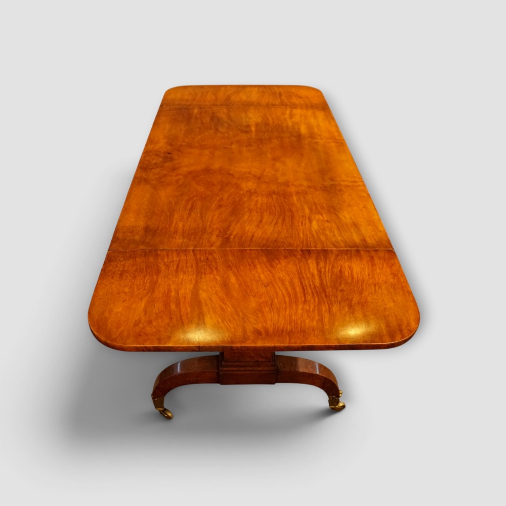 A Regency burr satinwood sofa table with drop leaves, two frieze drawers, brass handles, and splayed legs on castors. View VII