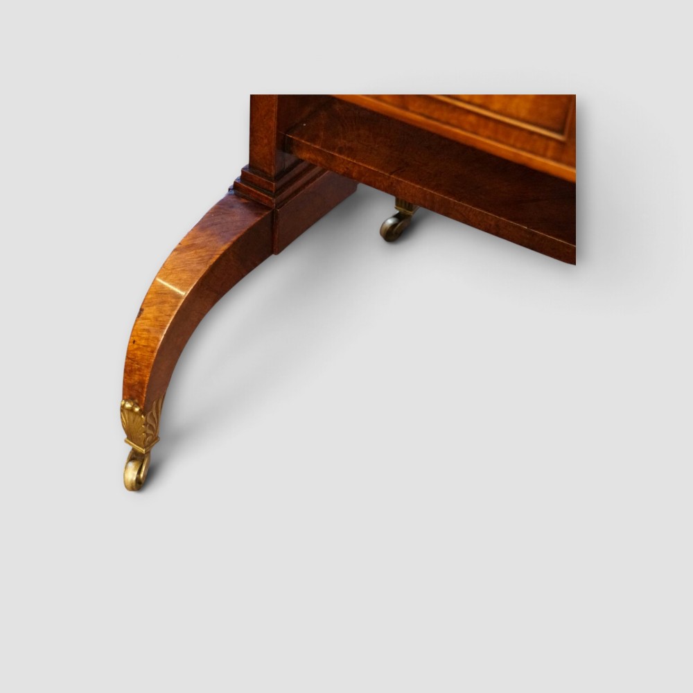 A Regency burr satinwood sofa table with drop leaves, two frieze drawers, brass handles, and splayed legs on castors. View IX