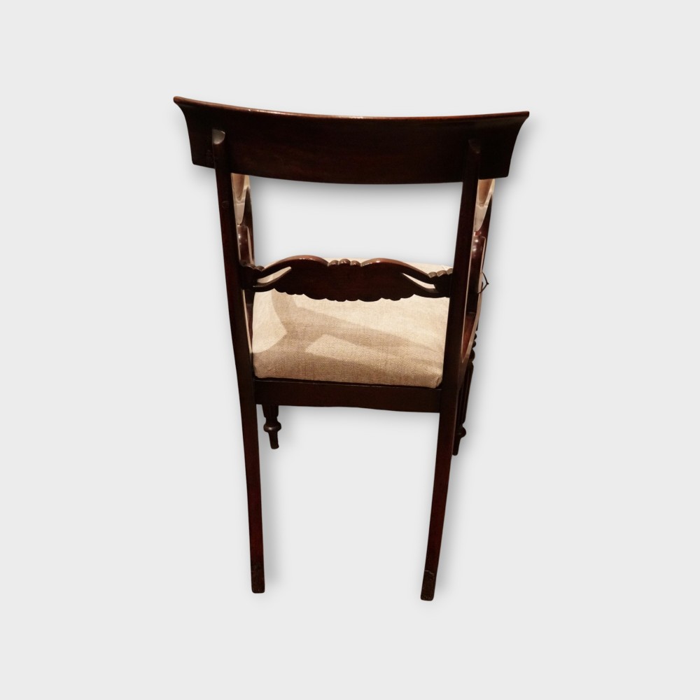 A set of eight William IV dark mahogany dining chairs comprising six side chairs and two carvers with turned front legs and light neutral upholstered seats. View VI