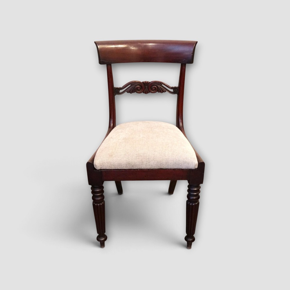 A set of eight William IV dark mahogany dining chairs comprising six side chairs and two carvers with turned front legs and light neutral upholstered seats. View VII