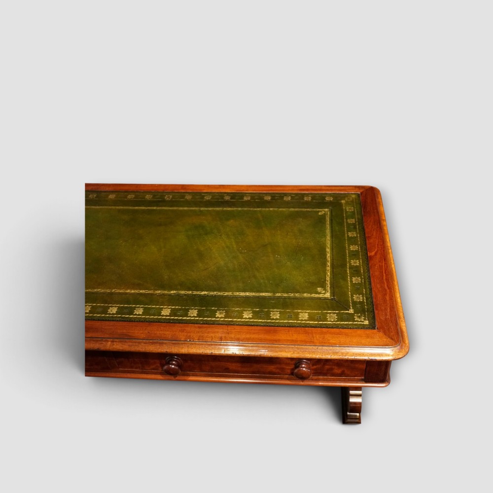An early Victorian mahogany writing table featuring a green leather inset top with gilt tooling, two frieze drawers, a turned stretcher, and end supports. View VIII