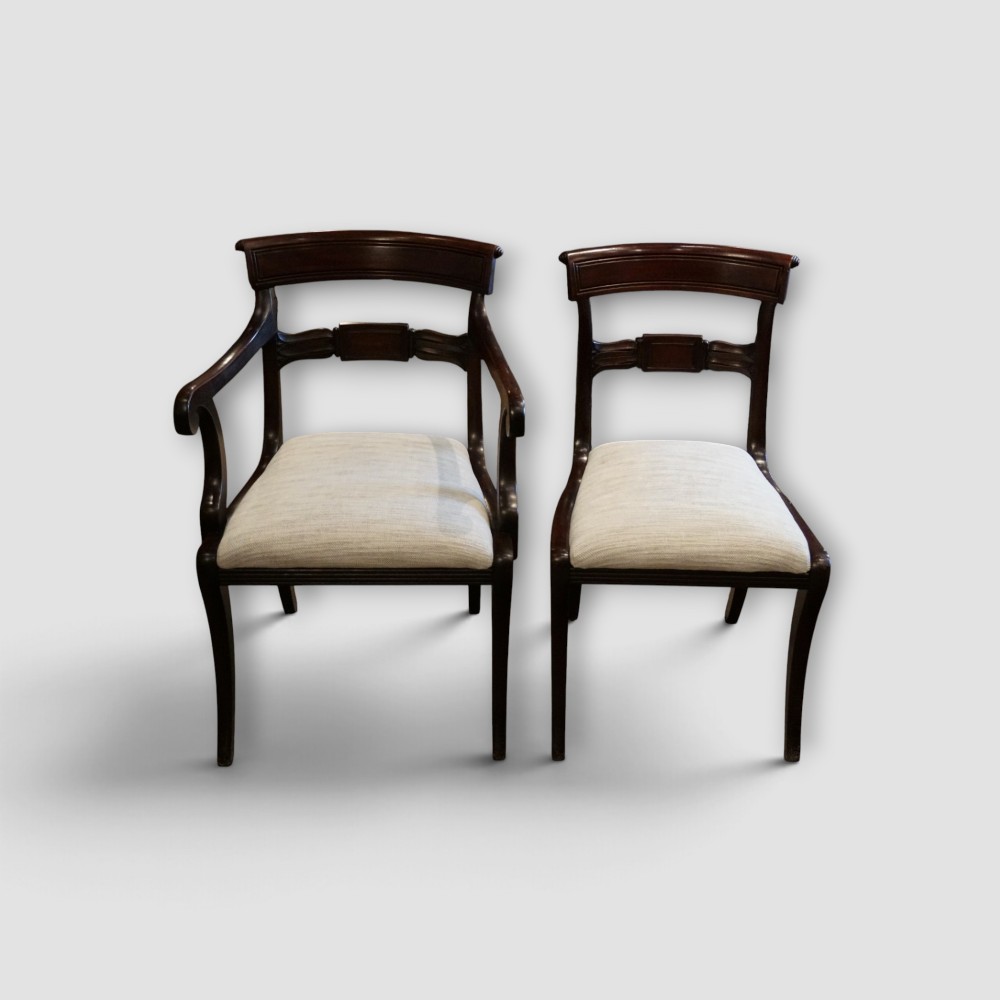 A set of eight Regency mahogany dining chairs with neutral cream upholstery, carved back rails, and curved sabre legs. View II