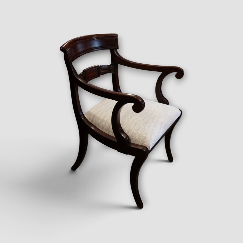 A set of eight Regency mahogany dining chairs with neutral cream upholstery, carved back rails, and curved sabre legs. View IV