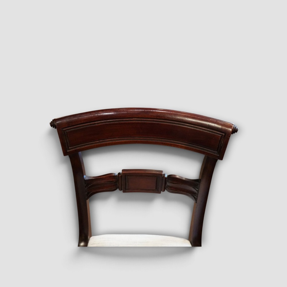 A set of eight Regency mahogany dining chairs with neutral cream upholstery, carved back rails, and curved sabre legs. View VI