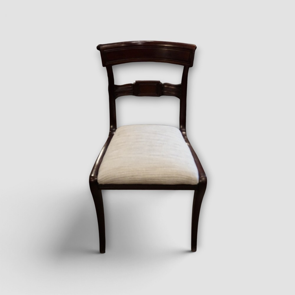 A set of eight Regency mahogany dining chairs with neutral cream upholstery, carved back rails, and curved sabre legs. View IX