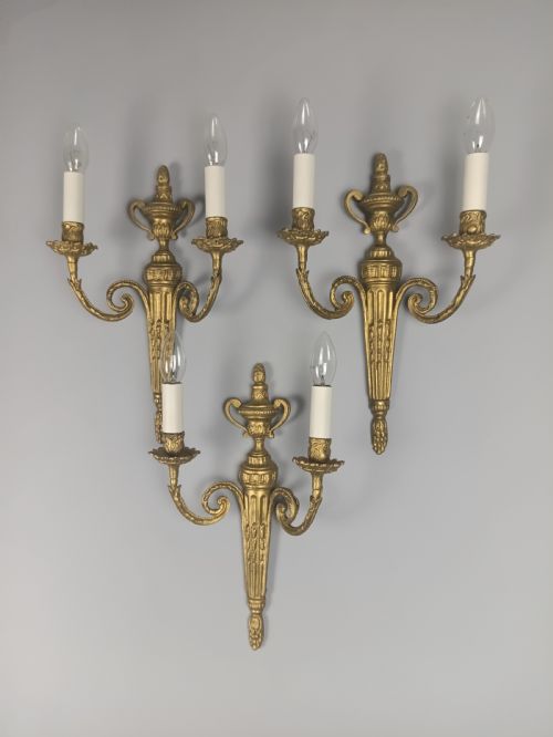 fig 1. Set of three French gilded brass wall sconces featuring twin scrolling arms and urn-shaped tapered backplates.
