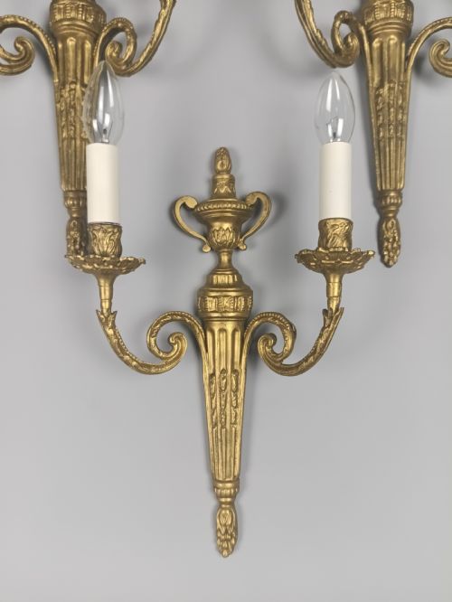 fig 3. Set of three French gilded brass wall sconces featuring twin scrolling arms and urn-shaped tapered backplates.