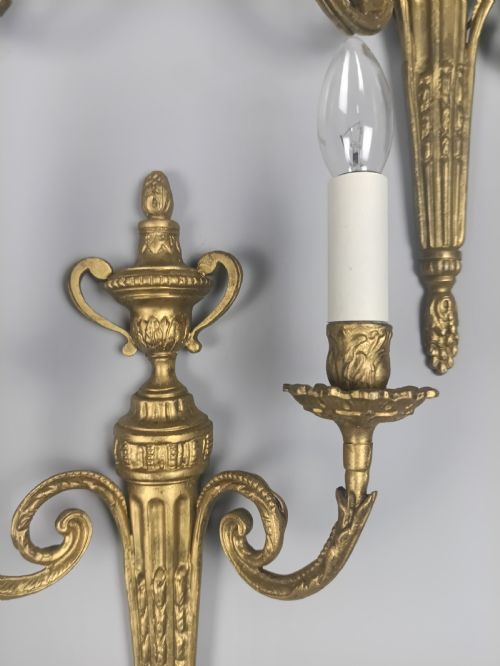 fig 4. Set of three French gilded brass wall sconces featuring twin scrolling arms and urn-shaped tapered backplates.