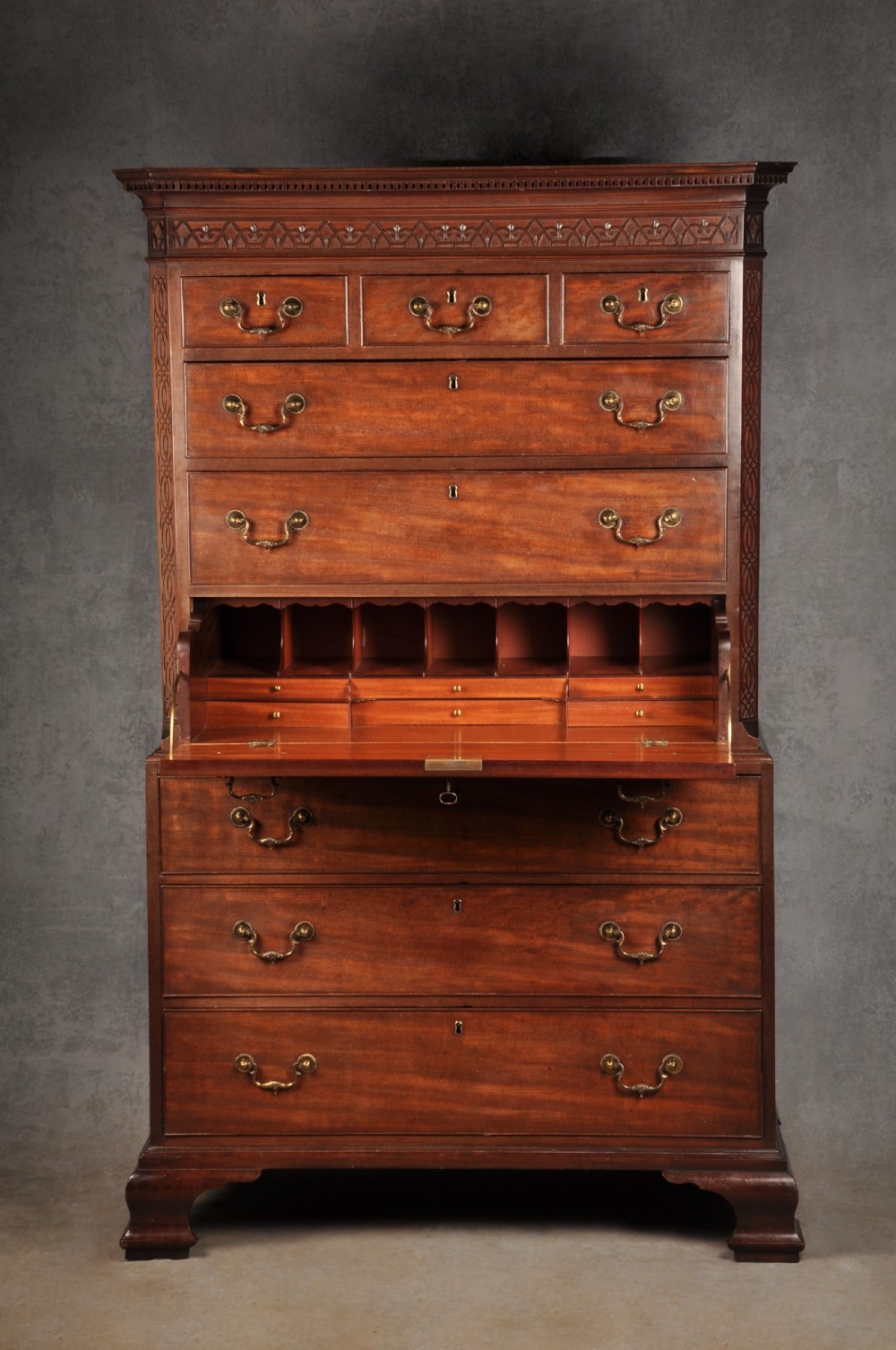 An 18th-century Georgian flame mahogany tallboy featuring a carved fretwork cornice, brass swan-neck handles, and ogee bracket feet. View II