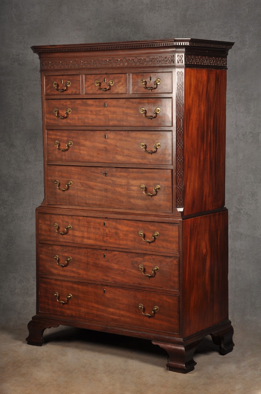 An 18th-century Georgian flame mahogany tallboy featuring a carved fretwork cornice, brass swan-neck handles, and ogee bracket feet. View III