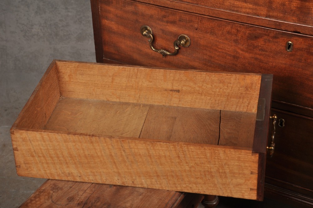 An 18th-century Georgian flame mahogany tallboy featuring a carved fretwork cornice, brass swan-neck handles, and ogee bracket feet. View XXI