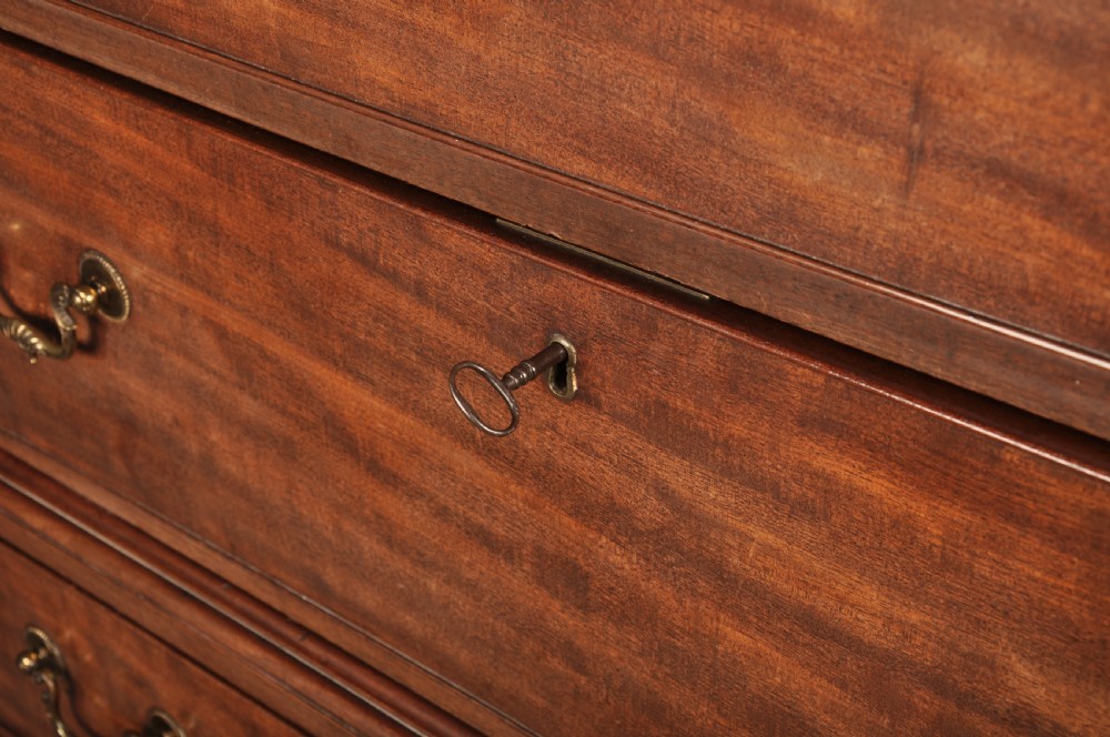 An 18th-century Georgian flame mahogany tallboy featuring a carved fretwork cornice, brass swan-neck handles, and ogee bracket feet. View XXII