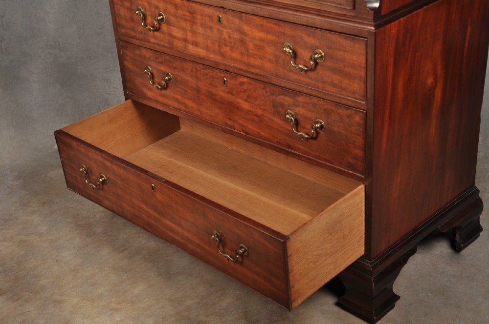 An 18th-century Georgian flame mahogany tallboy featuring a carved fretwork cornice, brass swan-neck handles, and ogee bracket feet. View XXIII