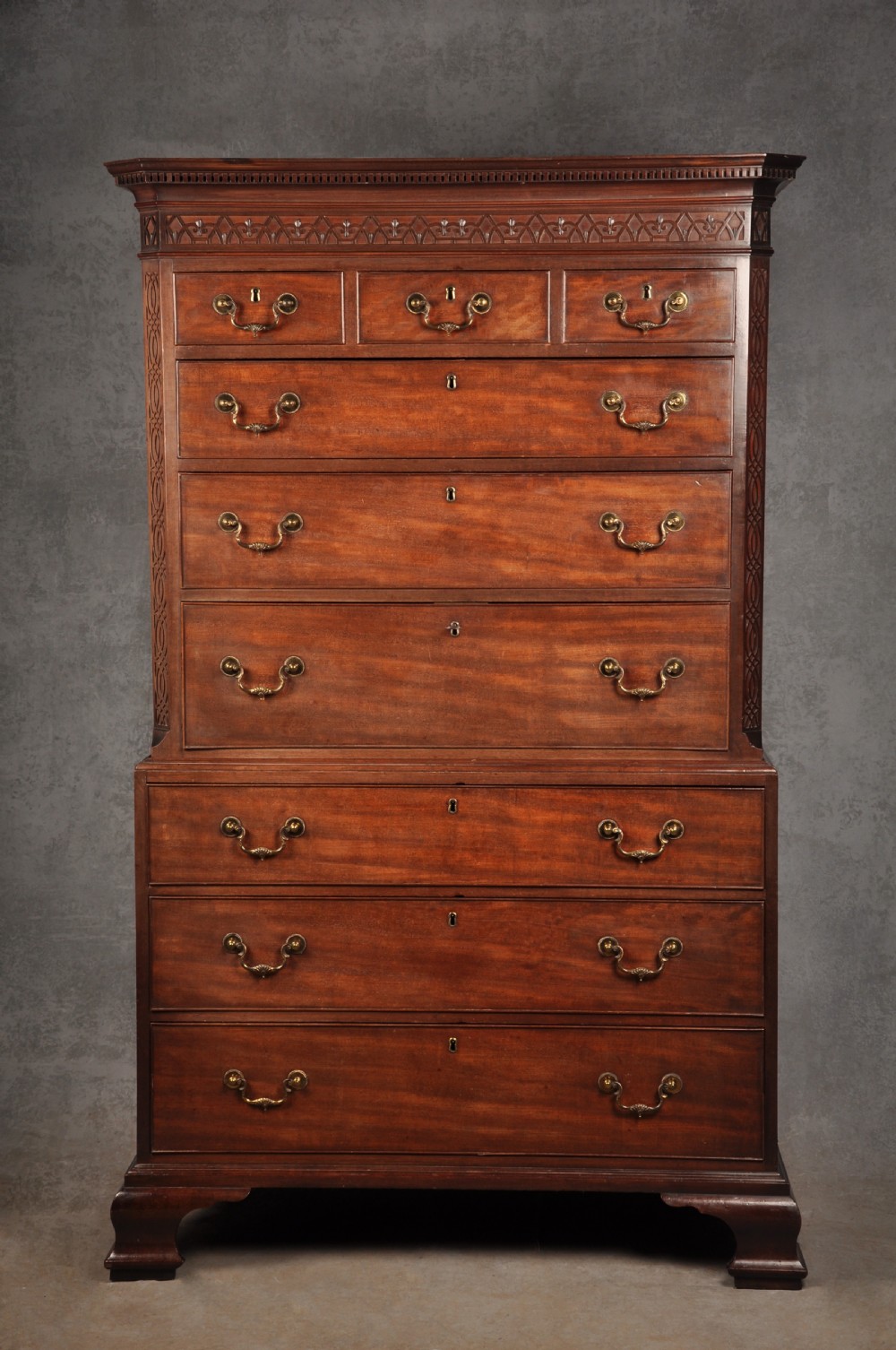 An 18th-century Georgian flame mahogany tallboy featuring a carved fretwork cornice, brass swan-neck handles, and ogee bracket feet. View XXIV