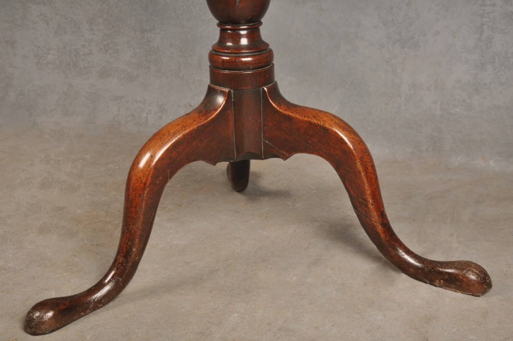 An 18th-century cherrywood tripod table featuring a circular top, turned baluster pedestal, and three splayed cabriole legs. View V