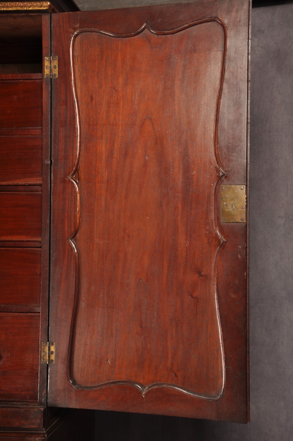 An 18th-century mahogany secretaire cabinet featuring twin upper doors with shaped gilded mouldings above an open fall-front desk with pigeonholes and three drawers on bracket feet. View VI