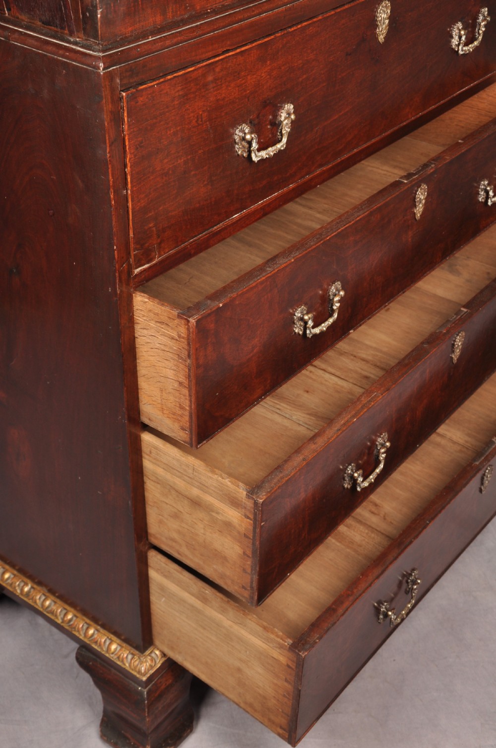 An 18th-century mahogany secretaire cabinet featuring twin upper doors with shaped gilded mouldings above an open fall-front desk with pigeonholes and three drawers on bracket feet. View XIV