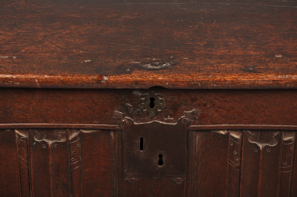 A Tudor era dark oak coffer featuring four carved linenfold panels and an iron lockplate on the front facade. View III