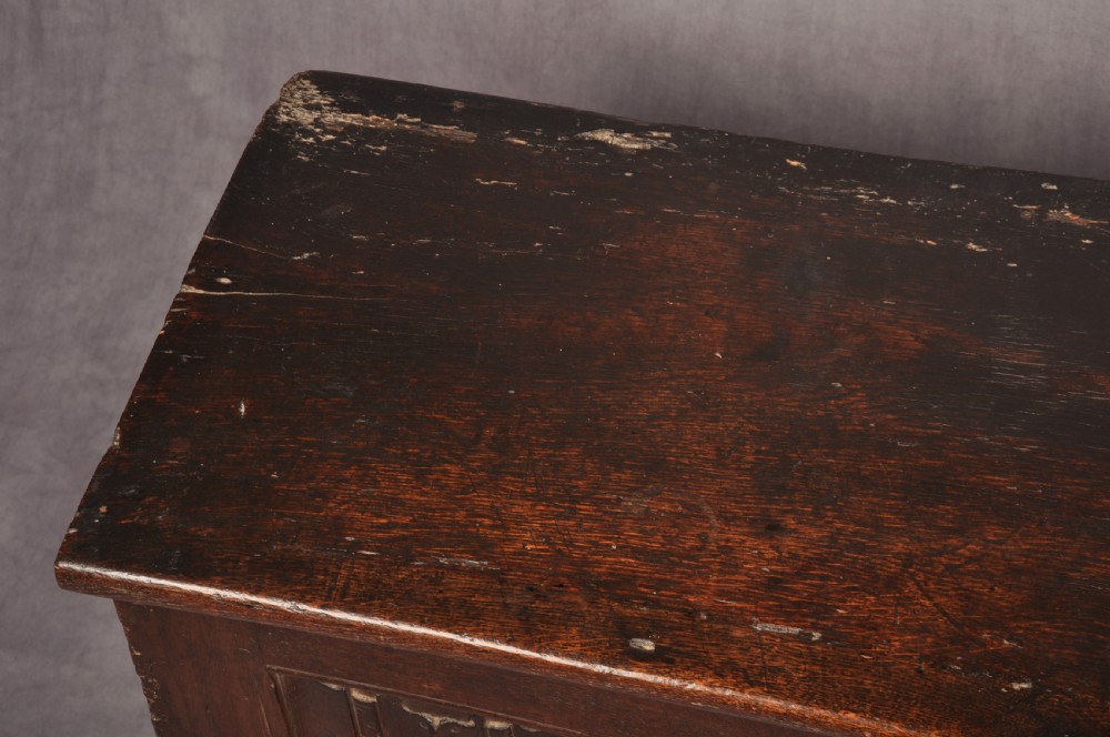 A Tudor era dark oak coffer featuring four carved linenfold panels and an iron lockplate on the front facade. View IV
