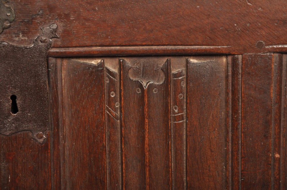 A Tudor era dark oak coffer featuring four carved linenfold panels and an iron lockplate on the front facade. View VI
