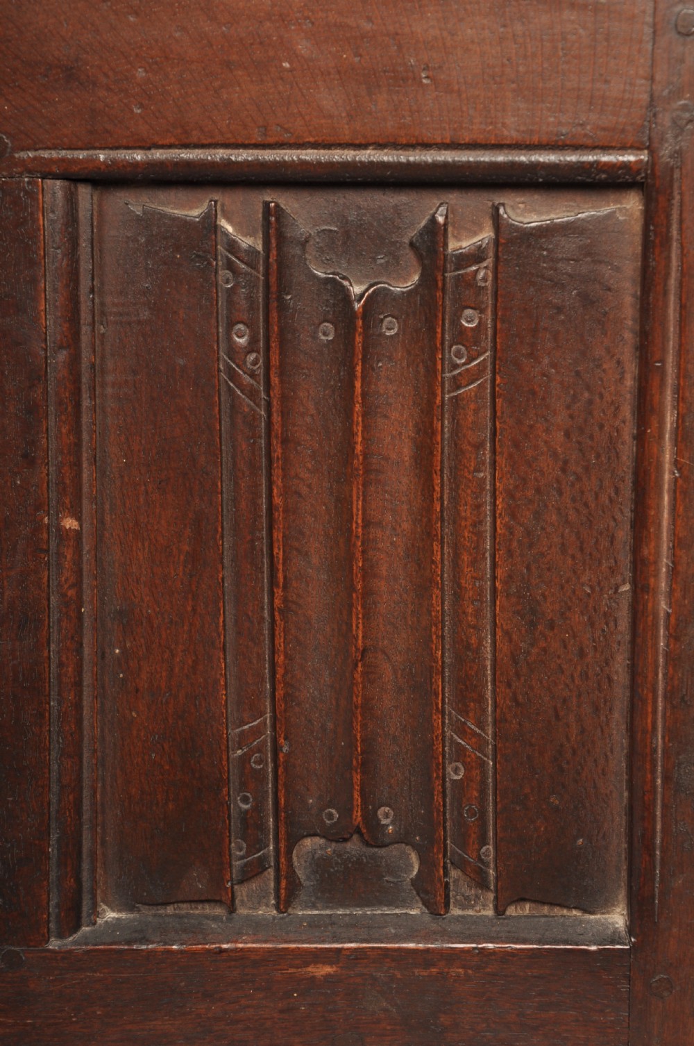 A Tudor era dark oak coffer featuring four carved linenfold panels and an iron lockplate on the front facade. View VII