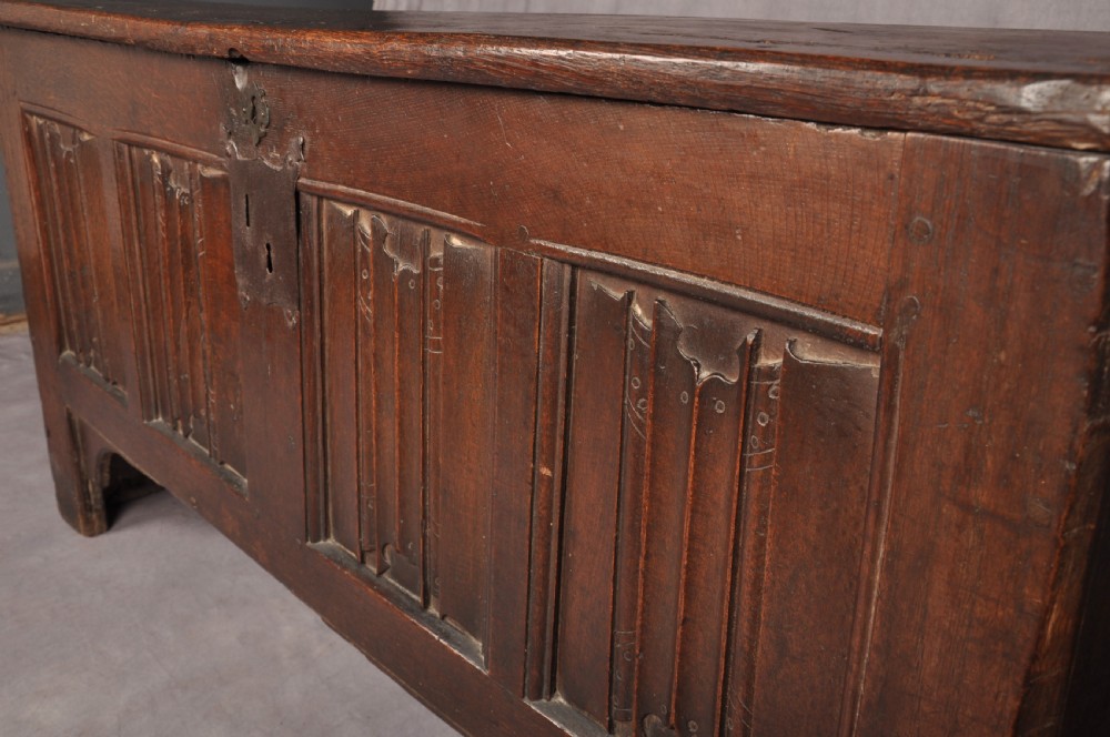 A Tudor era dark oak coffer featuring four carved linenfold panels and an iron lockplate on the front facade. View IX