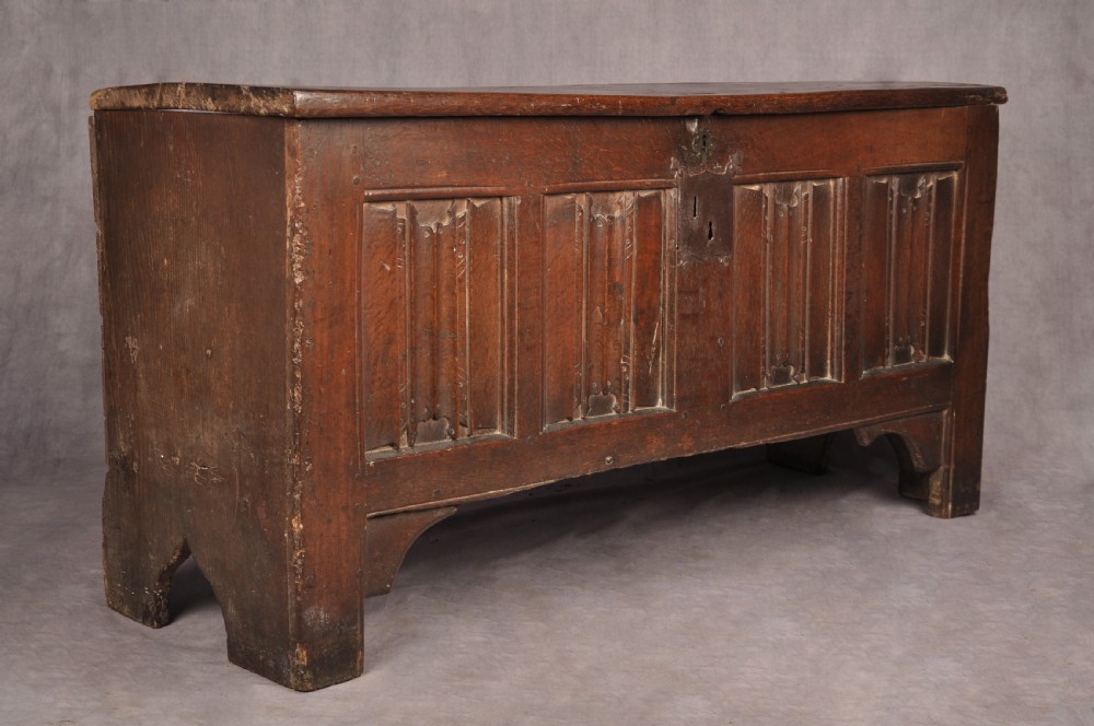 A Tudor era dark oak coffer featuring four carved linenfold panels and an iron lockplate on the front facade. View X