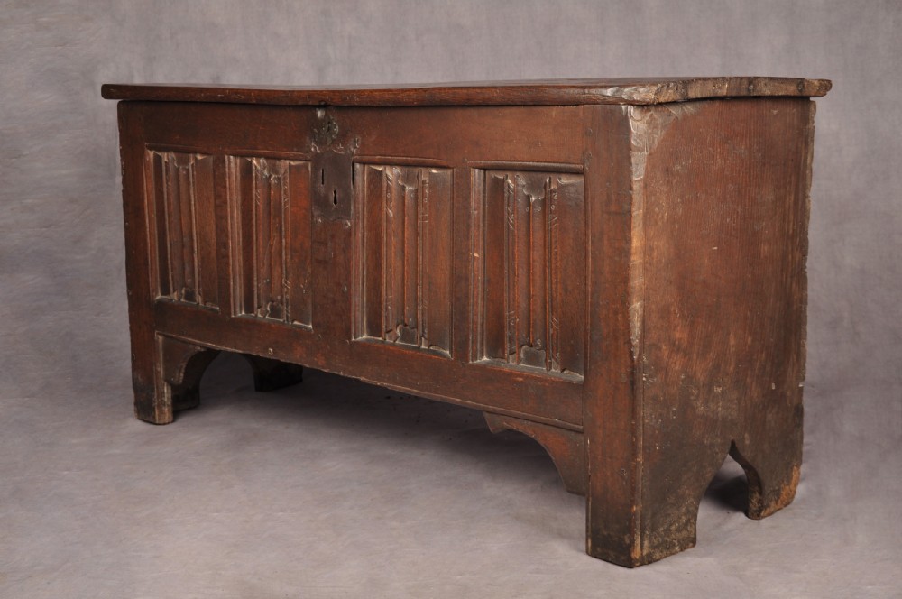 A Tudor era dark oak coffer featuring four carved linenfold panels and an iron lockplate on the front facade. View XI