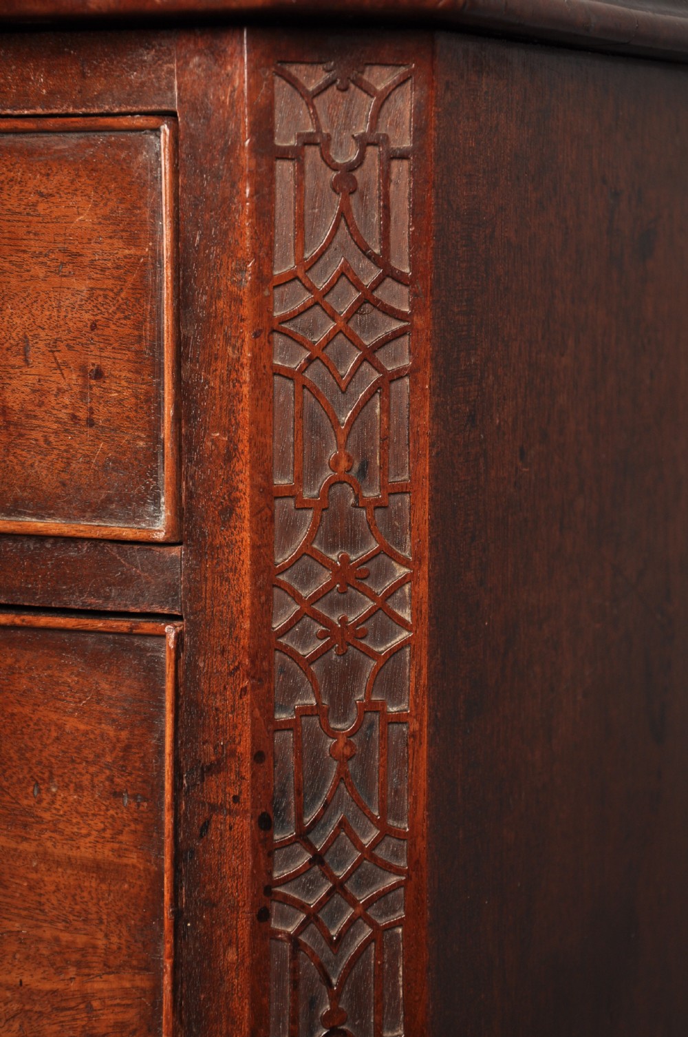 An 18th-century mahogany chest of drawers featuring two short over three long graduated drawers, carved blind fretwork stiles, brass swan-neck handles, and ogee bracket feet. View III