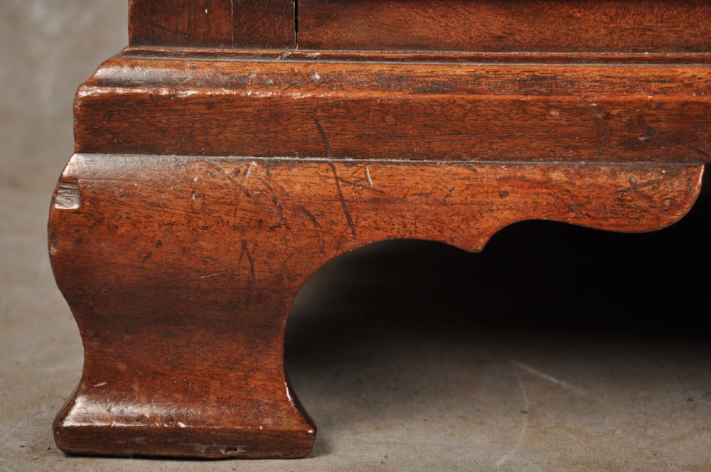 An 18th-century mahogany chest of drawers featuring two short over three long graduated drawers, carved blind fretwork stiles, brass swan-neck handles, and ogee bracket feet. View XII
