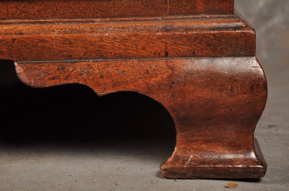 An 18th-century mahogany chest of drawers featuring two short over three long graduated drawers, carved blind fretwork stiles, brass swan-neck handles, and ogee bracket feet. View XIII