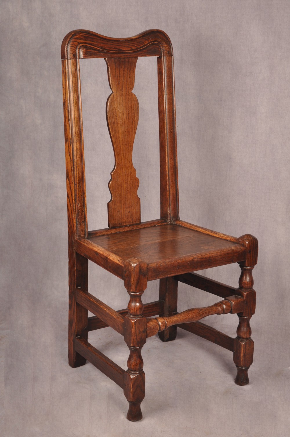 A set of four antique Queen Anne oak and elm side chairs featuring contoured vase backsplats, solid wooden seats, and turned front legs with stretchers. View II