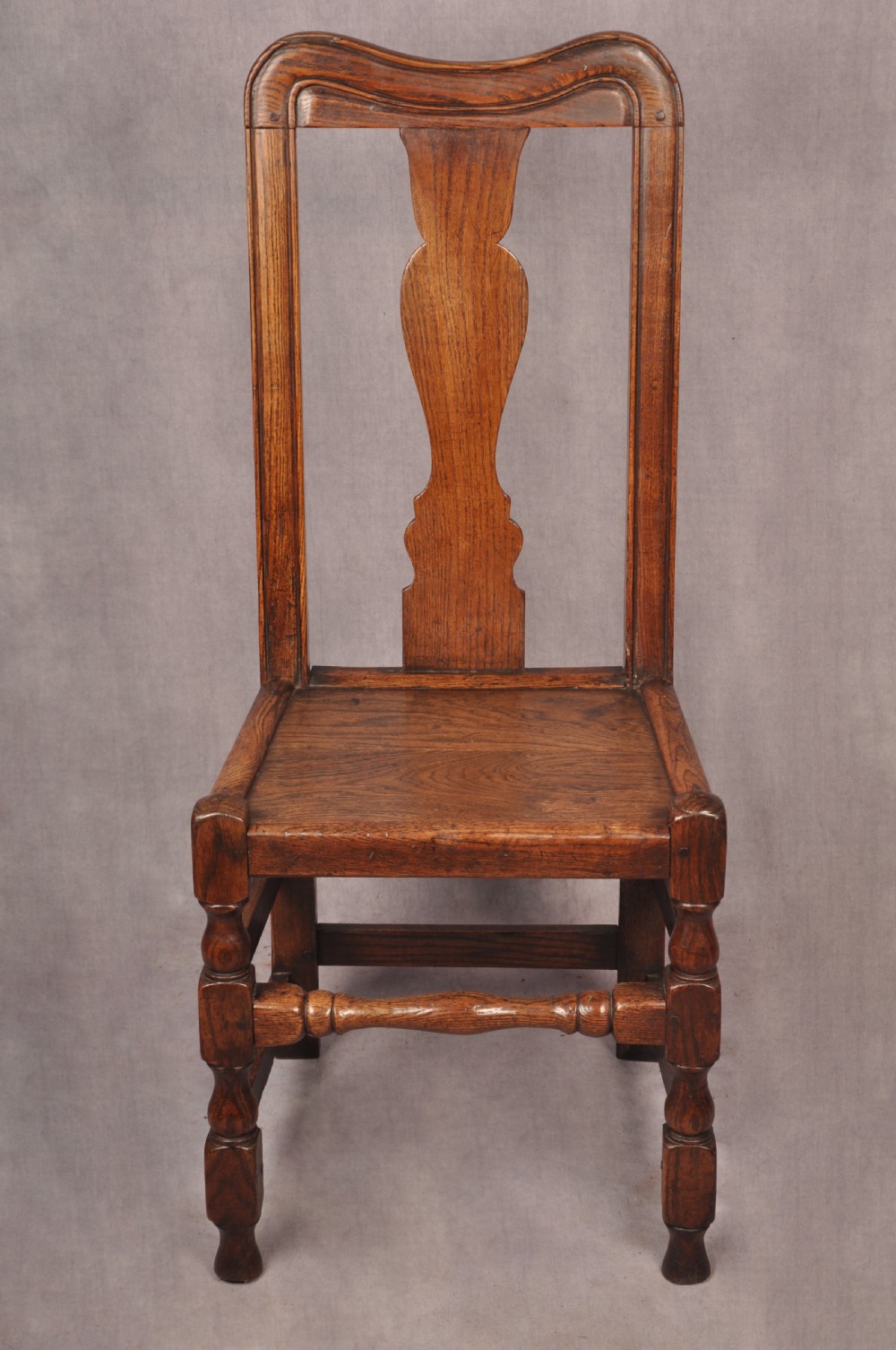 A set of four antique Queen Anne oak and elm side chairs featuring contoured vase backsplats, solid wooden seats, and turned front legs with stretchers. View III