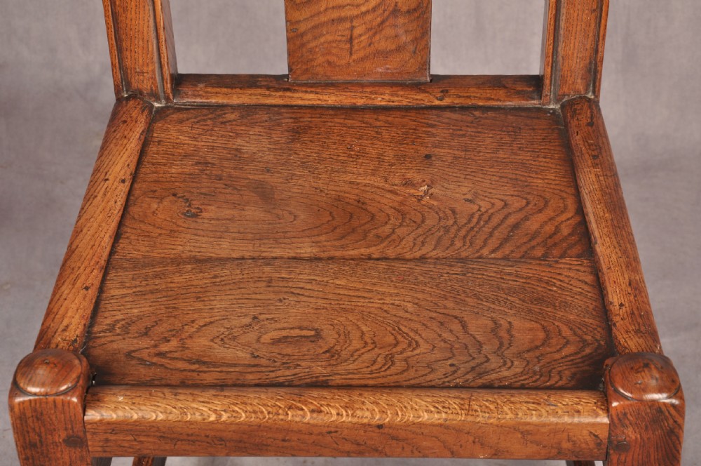 A set of four antique Queen Anne oak and elm side chairs featuring contoured vase backsplats, solid wooden seats, and turned front legs with stretchers. View V