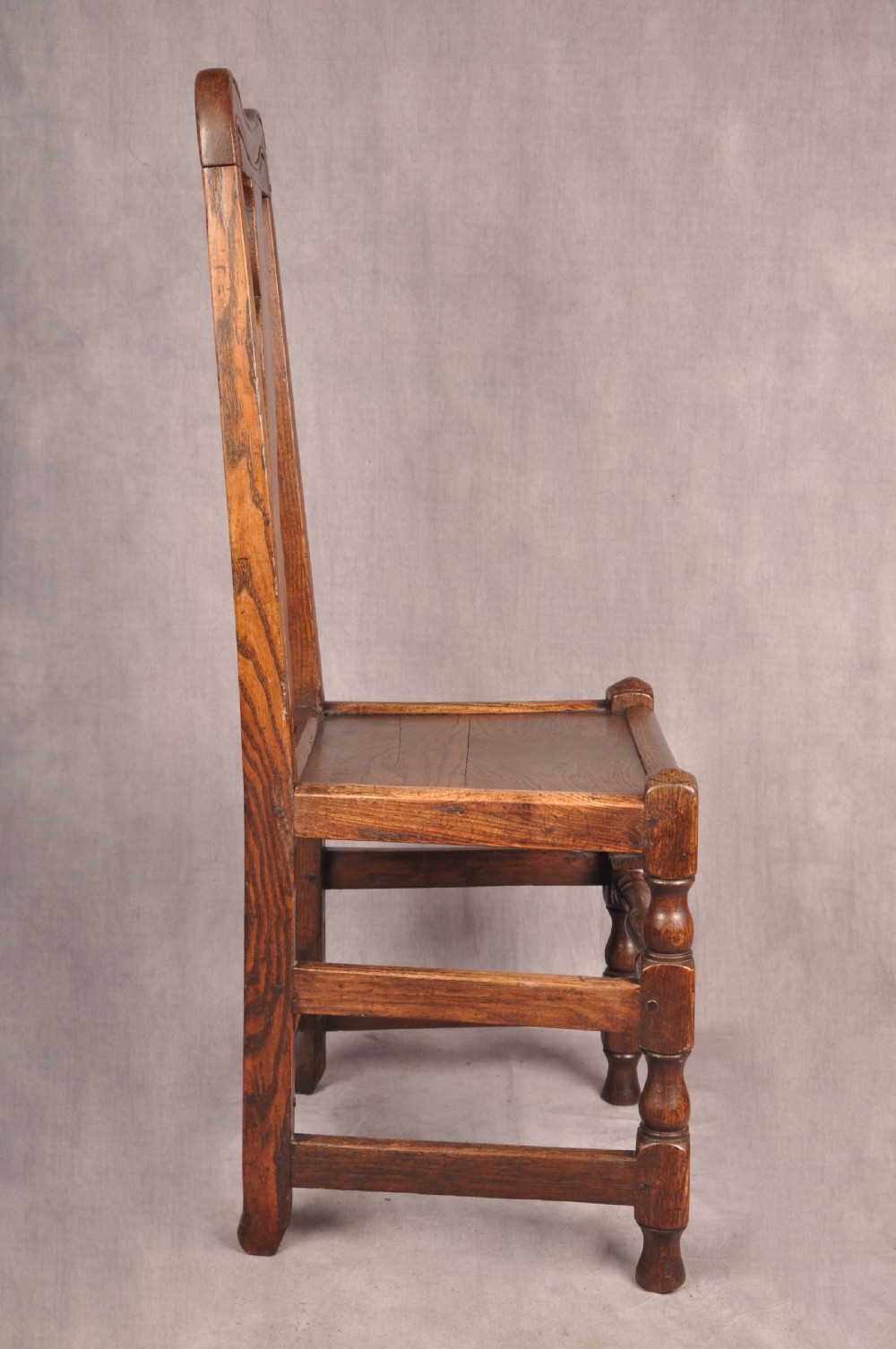 A set of four antique Queen Anne oak and elm side chairs featuring contoured vase backsplats, solid wooden seats, and turned front legs with stretchers. View VIII