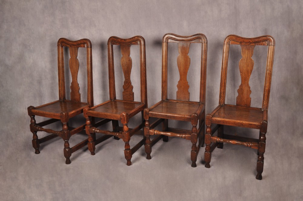 A set of four antique Queen Anne oak and elm side chairs featuring contoured vase backsplats, solid wooden seats, and turned front legs with stretchers. View X