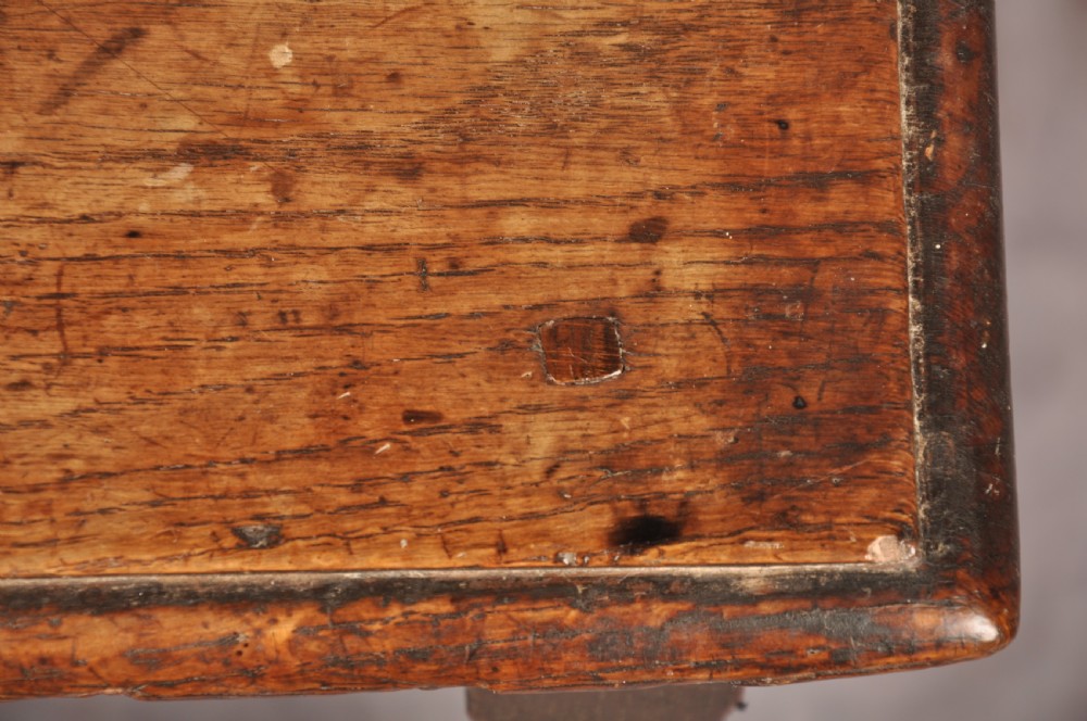 A dark oak joint stool featuring a rectangular moulded top above a carved frieze, supported by turned legs joined by low stretchers. View IV