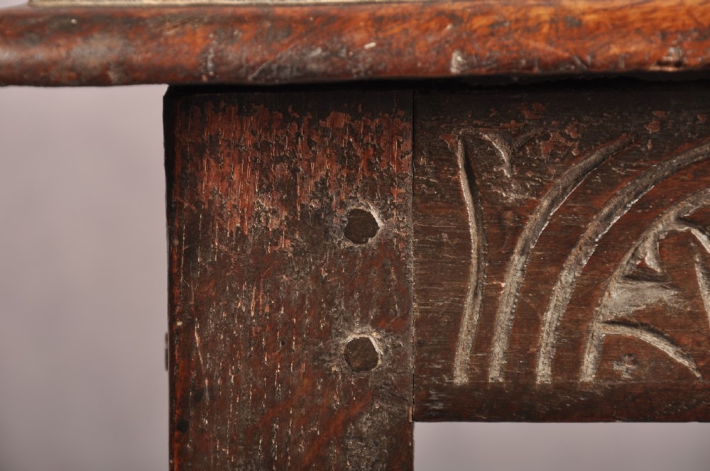 A dark oak joint stool featuring a rectangular moulded top above a carved frieze, supported by turned legs joined by low stretchers. View VII