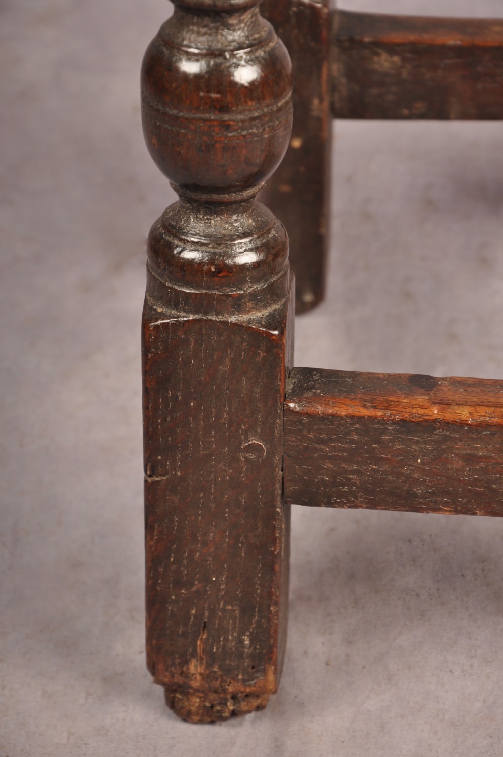 A dark oak joint stool featuring a rectangular moulded top above a carved frieze, supported by turned legs joined by low stretchers. View X