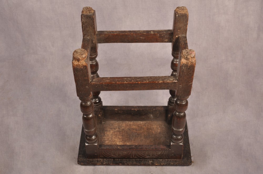 A dark oak joint stool featuring a rectangular moulded top above a carved frieze, supported by turned legs joined by low stretchers. View XI
