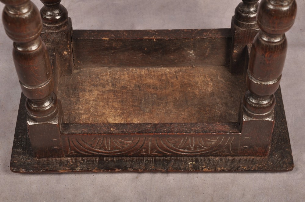 A dark oak joint stool featuring a rectangular moulded top above a carved frieze, supported by turned legs joined by low stretchers. View XIII