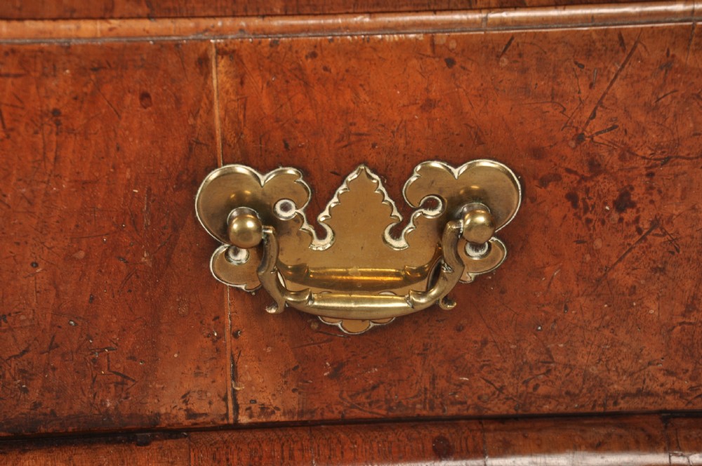 An early eighteenth-century walnut bureau with a sloping fall front, four drawers, decorative brass handles, and bracket feet. View II