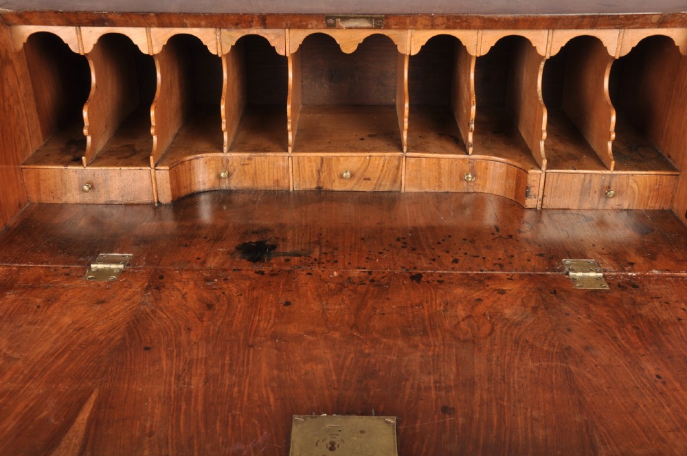 An early eighteenth-century walnut bureau with a sloping fall front, four drawers, decorative brass handles, and bracket feet. View VIII